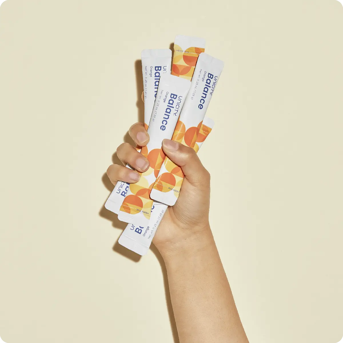 Hand holding stick packs of Balance Unicity