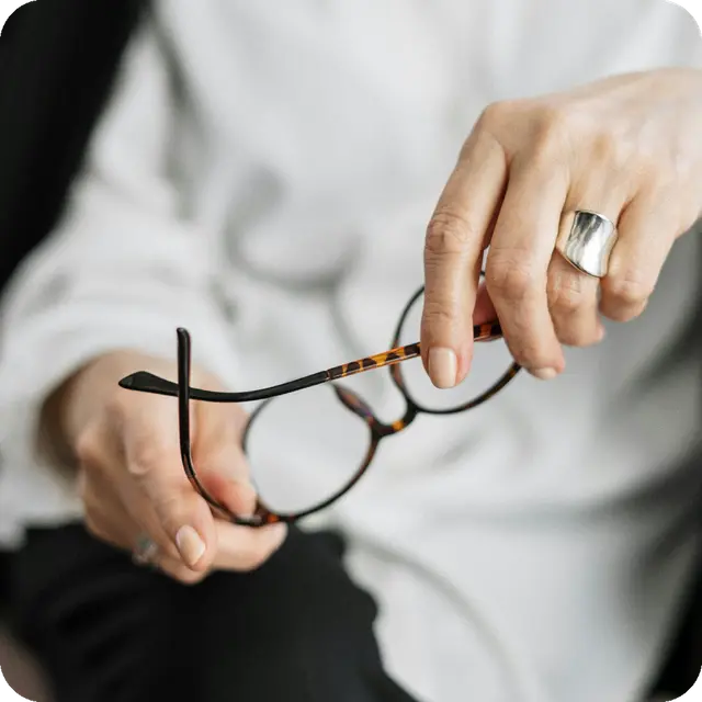 Mujer sosteniendo gafas en las manos
