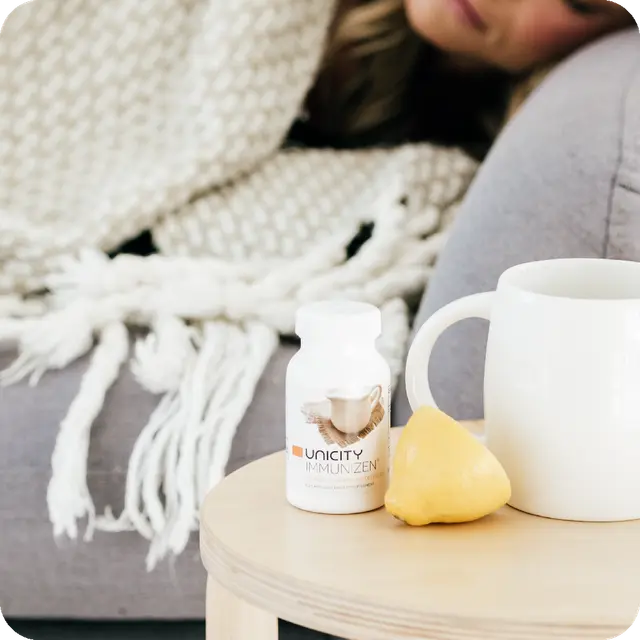 Lady sleeping next to bottle of Immunizen by Unicity