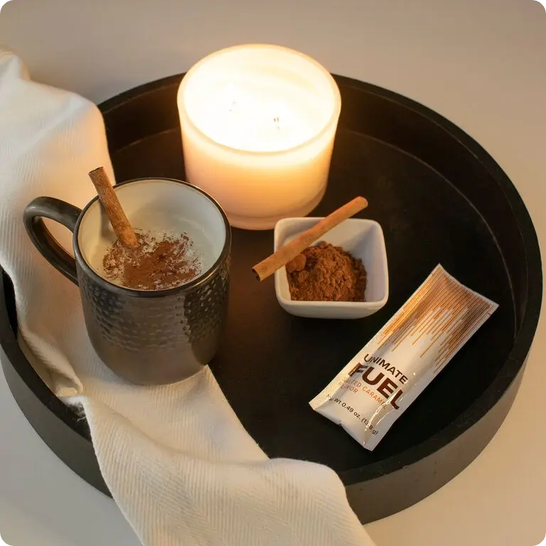 Mug of Unimate Fuel Salted Caramel next to candle and sachet